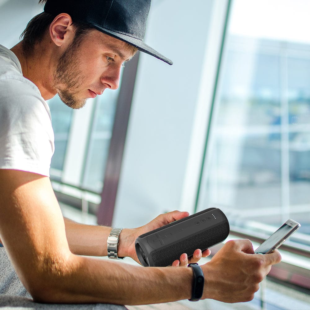GLOWBEATS Wireless Bluetooth Speaker, Black, with an individual navigating the Bluetooth connection from his smartphone.