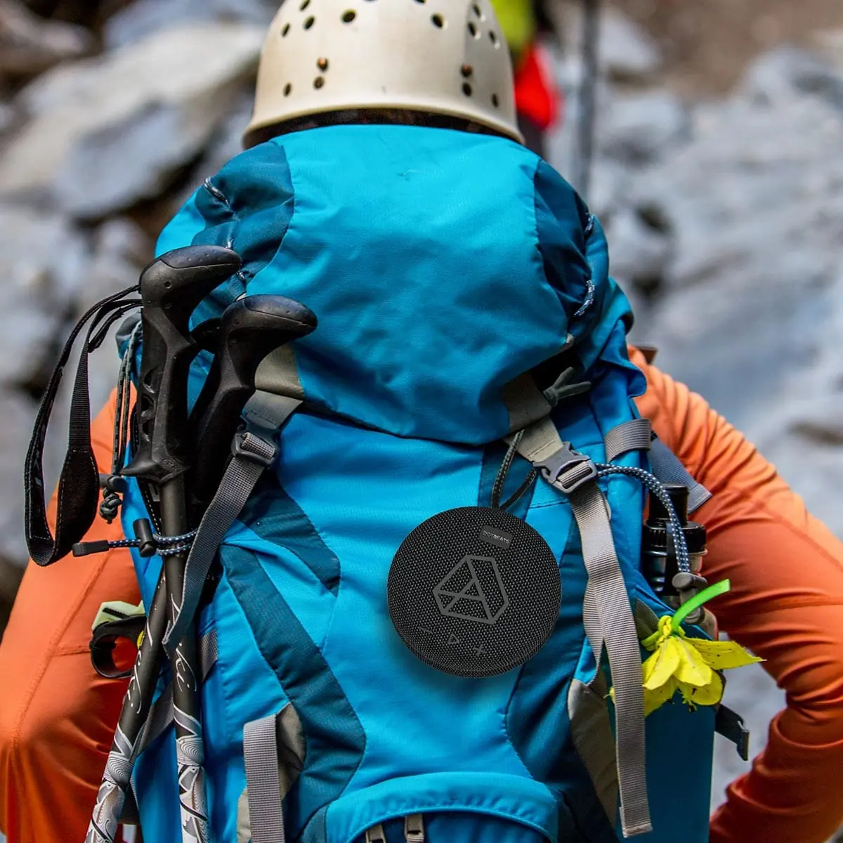 DOTBEATS Mini Wireless Bluetooth Speaker, Black, dangling from a hiker's back pack.