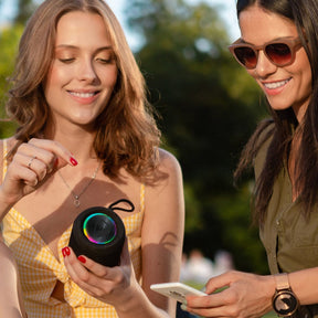 GLOWBEATS Wireless Bluetooth Speaker, Black, with two individuals navigating the Bluetooth connection from a smartphone.